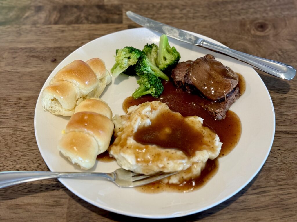 Plate with rolls, mashed potatoes, gravy, broccoli, and roast beef